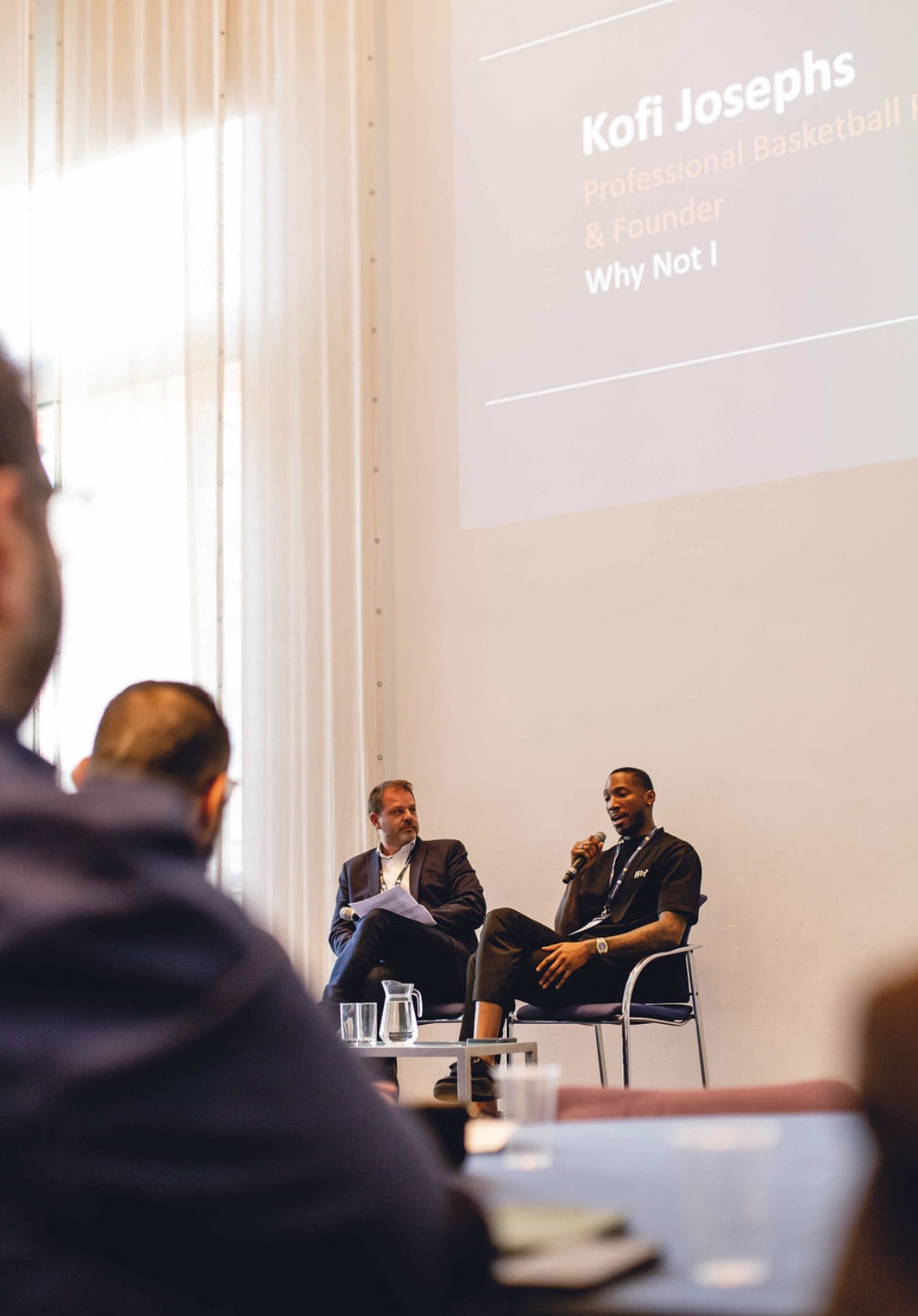 Kofi Josephs speaking on stage at a global corporate health conference